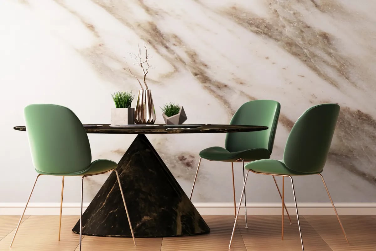 Stół okrągły z podstawą w kształcie stożka. Obok stołu krzesła z zielonym siedziskiem. Na stole wazon oraz inne dekoracje.