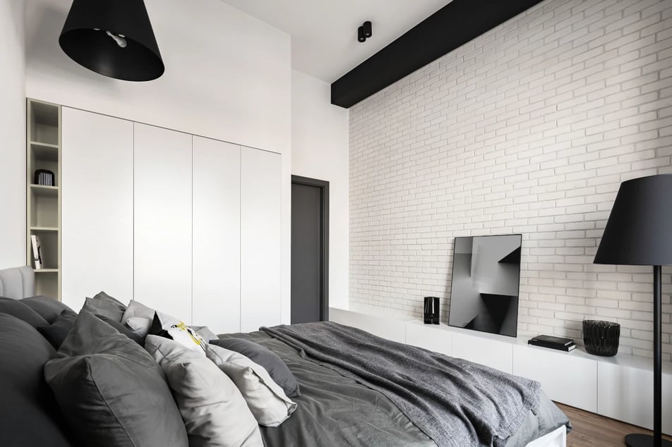 Mała sypialnia w trzech kolorach: biel, szarość oraz czerń.  Meble w kolorze białym, natomiast dodatki w kolorze szarym i czarnym.