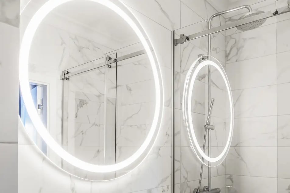 Jasna łazienka z ścianami marmurowymi z lustrami podświetlanymi.