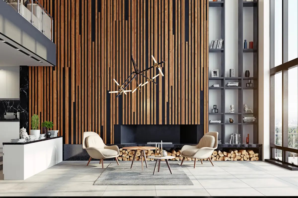 Lamele położone na ścianie z kominkiem. Połączenie drewna z czernią. Dwa fotele postawione przy stoliku kawowym. Obok kominka regały z dekoracjami oraz książkami.