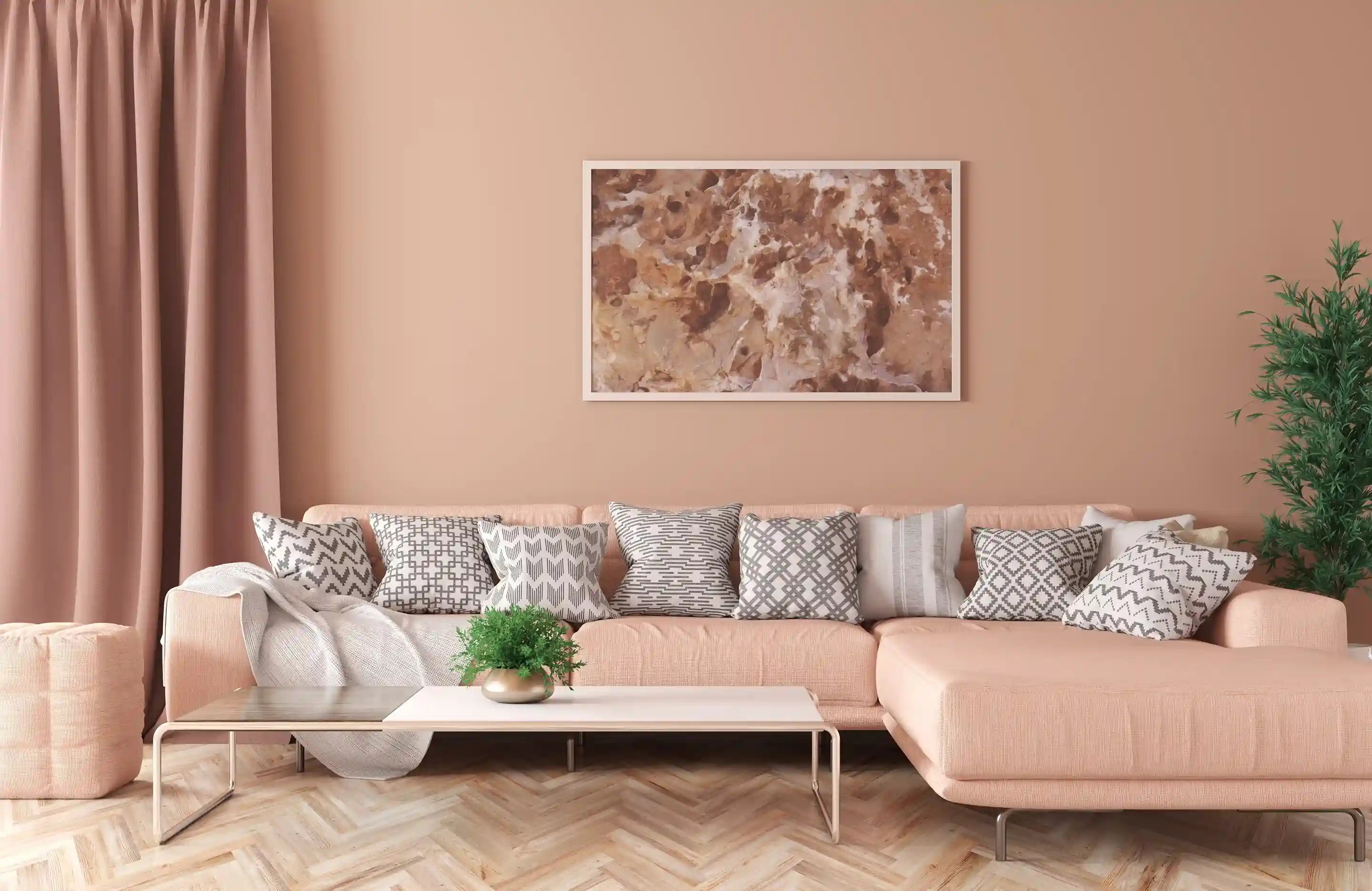 Salon w stylu minimalistycznym w kolorze peach fuzz. W centrum znajduje się różowa kanapa, na niej poduszki, a nad nią obraz. Przed kanapą stoi stolik.