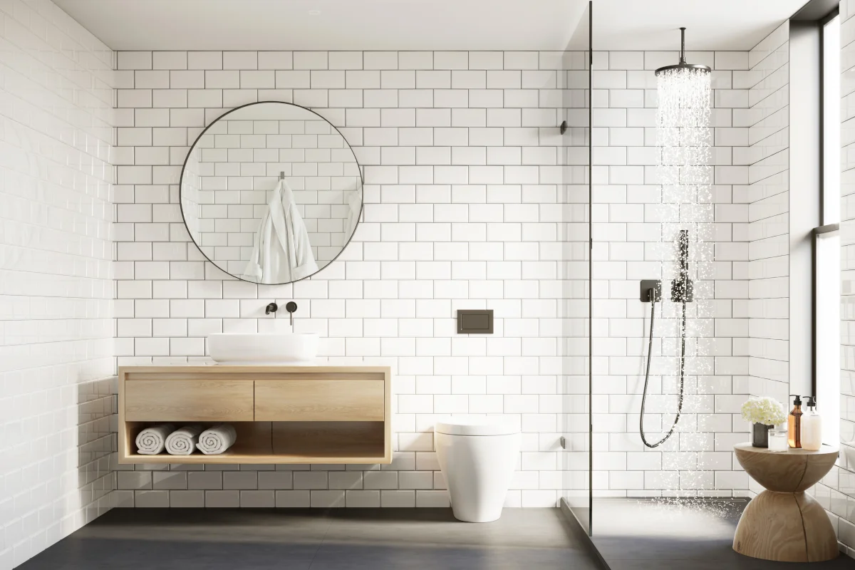 Łazienka w kolorze białym z kabiną prysznicową i zawieszonym okrągłym lustrem.