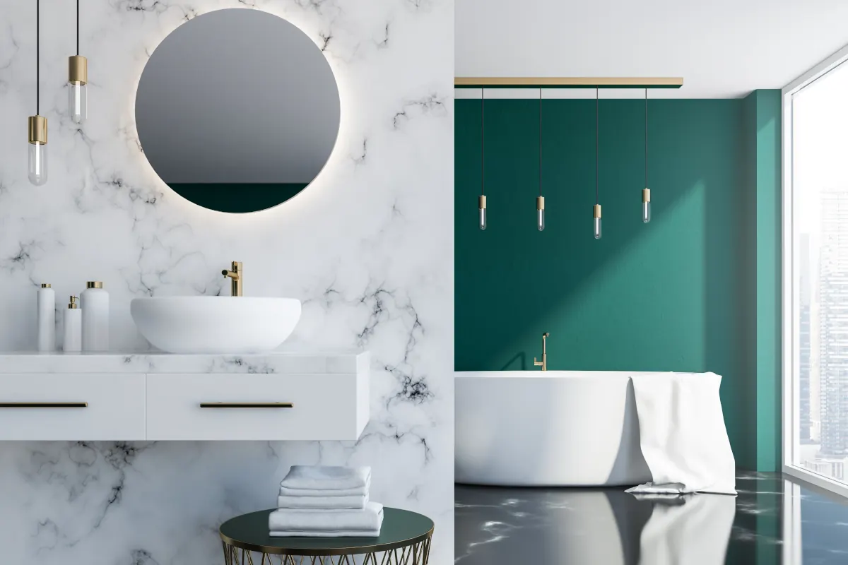 Łazienka w stylu glamour. Umywalka na tle ściany marmurowej. W drugiej części łazienki wolnostojąca wanna i ściana pomalowana na zielono. 