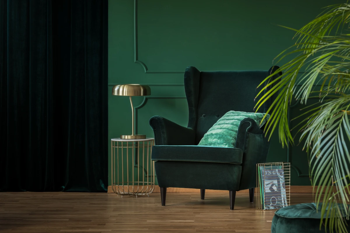 Zielony fotel z poduszką na tle zielonej ściany z dodatkami glamour.