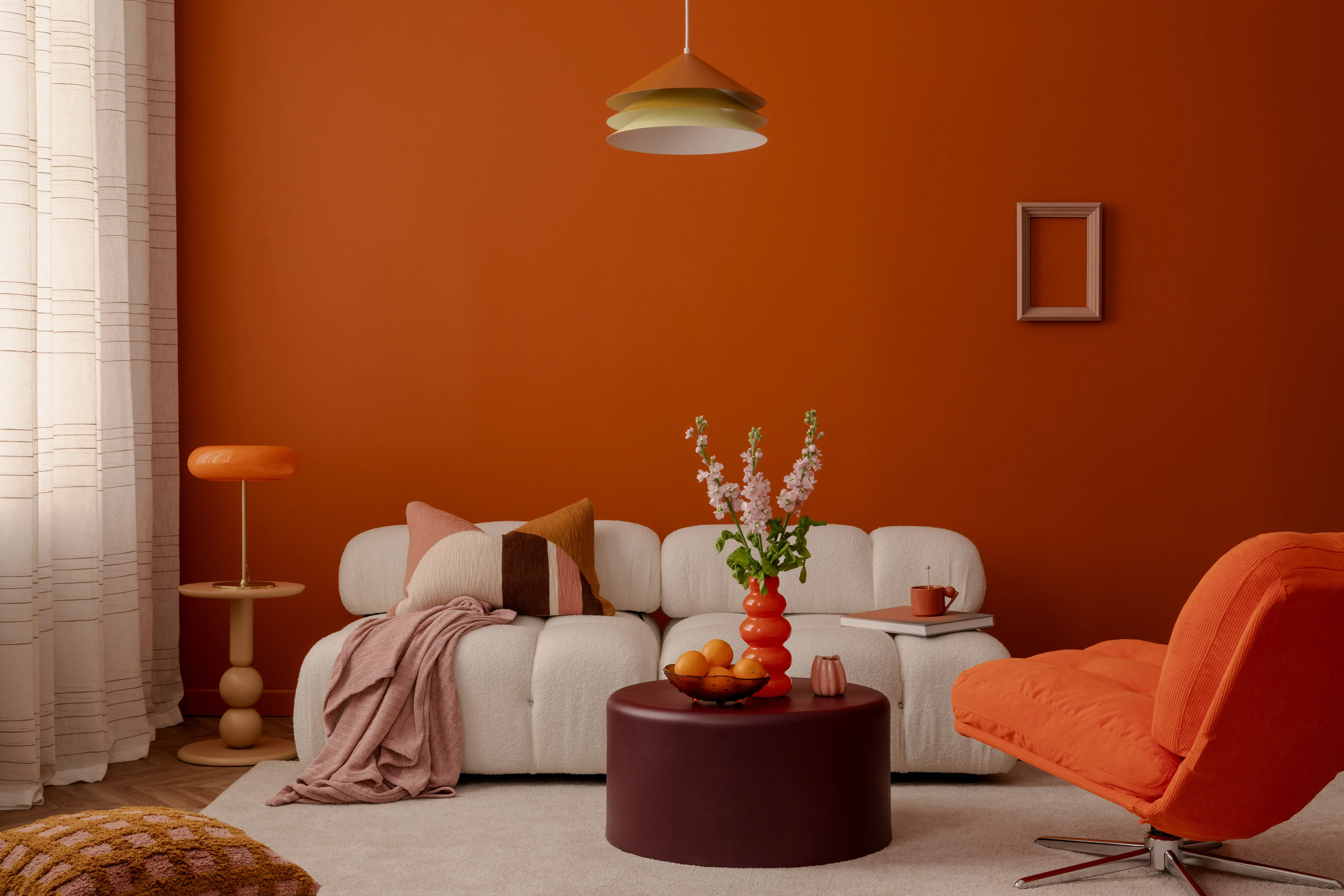 Salon w stylu nowoczesnym ze ścianami w kolorze ceglanym, białą kanapą i poduszkami na niej.